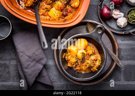 Hausgemachtes Gulasch mit Kartoffeln und Sauerkraut. Eintopf mit Rindfleisch und Gemüse, gekocht in Tontopf Stockfoto