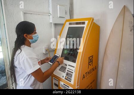 Chiltuipan, El Salvador. Juni 2021. Eine Frau zieht Geld von einem Bitcoin-Geldautomaten ab. Der salvadorianische Präsident Nayib Bukele hat angekündigt, dass er dem Kongress ein Gesetz vorschlagen wird, in dem seine Partei die Mehrheit kontrolliert, damit Bitcoin zum legalen Zahlungsmittel wird. El Salvador würde das erste Land der Welt werden, das eine Kryptowährung als gesetzliches Zahlungsmittel akzeptiert. Kredit: SOPA Images Limited/Alamy Live Nachrichten Stockfoto