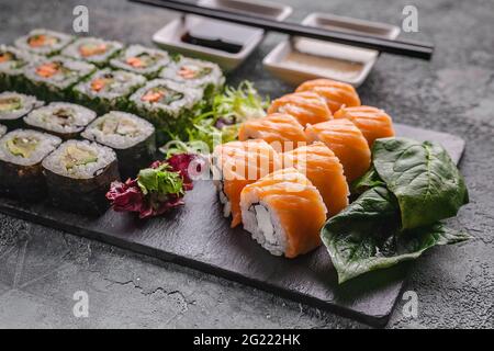 Nahaufnahme appetitliche Brötchen mit Lachs und Philadelphia Frischkäse mit frischem, leckerem Salat auf einem Schneidebrett aus schwarzem Stein. Stockfoto