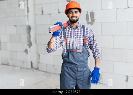 Mason überprüft die horizontale Ebene der Hauswandschicht, die aus belüftelten, autoklavierten Betonblöcken besteht Stockfoto