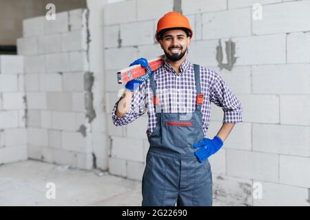 Mason überprüft die horizontale Ebene der Hauswandschicht, die aus belüftelten, autoklavierten Betonblöcken besteht Stockfoto