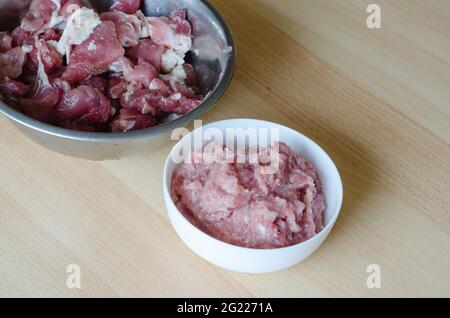 Schritt für Schritt Zubereitung von hausgemachtem gehacktem Schinken. Schritt 6: Eine Metallschüssel mit großen Fleischstücken und einen weißen Teller mit Hackfleisch. Kochrezept. Stockfoto