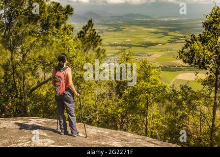 Eine alleinstehende Wanderin mit Wanderstöcken steht auf dem natürlichen Aussichtspunkt auf dem Pyramid-Wanderweg in Gordonvale, Queensland, Australien. Stockfoto