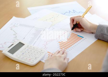 Nahaufnahme der Geschäftsfrau Analyse von Graphen mit Rechner am Schreibtisch Stockfoto