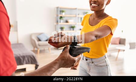 Kurier Gibt Dem Kunden Terminal Zur Bezahlung Mit Smartwatch Zu Hause Stockfoto