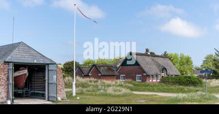 Sonderho, Dänemark - 29. Mai 2021: Typische dänische Backsteinhäuser und ein Bootshaus und eine Flagge im Vordergrund auf der Insel Fano Stockfoto