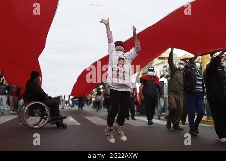 Lima, Peru. Juni 2021. Ein Mädchen springt, um eine riesige peruanische Flagge zu berühren, die von Anhängern des Kandidaten Pedro Castillo während einer Kundgebung hochgehalten wird. In einem extrem engen Rennen bei den Präsidentschaftswahlen in Peru liegt der linke Kandidat Pedro Castillo knapp vor uns. Kredit: Cesar Campos/dpa/Alamy Live Nachrichten Stockfoto