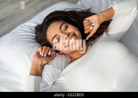 Glückliche afroamerikanische Frau, die sich nach dem Aufwachen dehnt Stockfoto