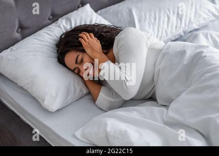 Schwarze Frau weinend, liegend im Bett bedeckendes Gesicht Stockfoto