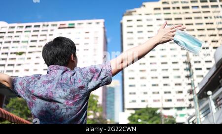 Junger Mann, der eine Gesichtsmaske auszieht und im Freien tief einatmet - Ende des Covid-19- und Coronavirus-Konzepts Stockfoto