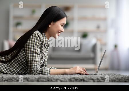 Seitenansicht der asiatischen jungen Frau mit Laptop zu Hause Stockfoto