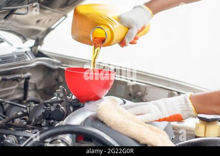 Automechaniker gießt neues Öl an den Motor. Stockfoto