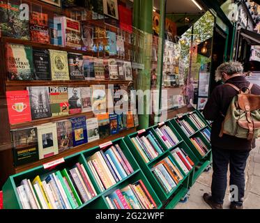 Fenster des Buchladens an der Charing Cross Road, London; Mann, der die reduzierten Bücher vor dem Hotel durchstöbert Stockfoto