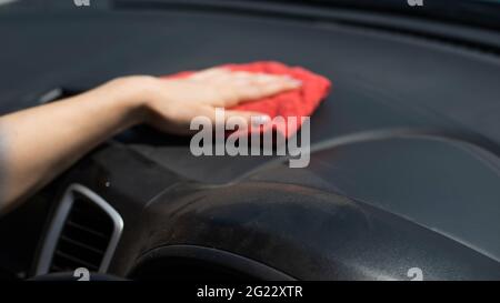 Frau wischt das Armaturenbrett des Autos von Staub ab. Stockfoto