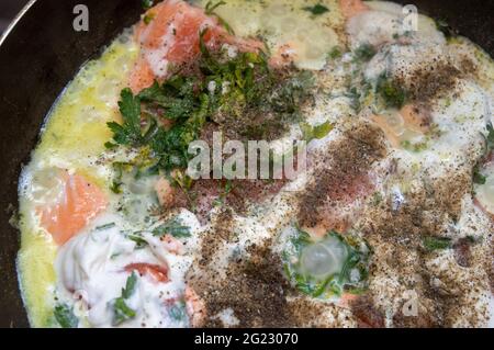 Lachsscheiben in einer Pfanne mit Petersilie. Lachs in Sahnesauce wird in einer Pfanne gebraten Stockfoto
