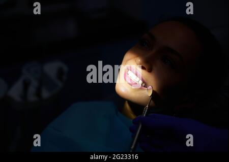 Nahaufnahme einer Frau mit einem schönen, weißen Lächeln bei der Untersuchung in der Zahnmedizin. Konzept der oralen Gesundheitsversorgung Stockfoto