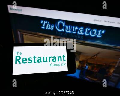 Person, die ein Smartphone mit dem Logo des britischen Pub-Unternehmens The Restaurant Group plc auf dem Bildschirm vor der Unternehmenswebsite hält. Konzentrieren Sie sich auf die Telefonanzeige. Stockfoto