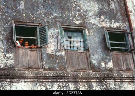 Kinder, die aus einem Fenster aus einem alten Gebäude in Stone Town, Sansibar, Tansania, schauen Stockfoto