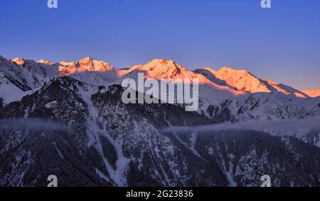 Weiches Morgenlicht auf Bergkämmen; felsige Berge, die bei Sonnenaufgang mit Schnee bedeckt sind Stockfoto