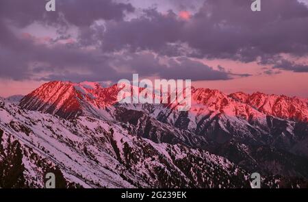 Weiches Morgenlicht auf Bergkämmen; felsige Berge, die bei Sonnenaufgang mit Schnee bedeckt sind Stockfoto