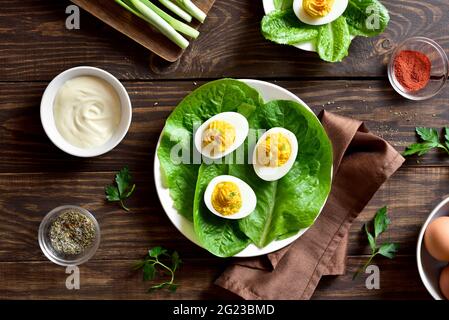 Auf dem Holzboden auf dem Teller devilierte Eier mit Paprika, Senf und Mayonnaise. Draufsicht, flach liegend Stockfoto