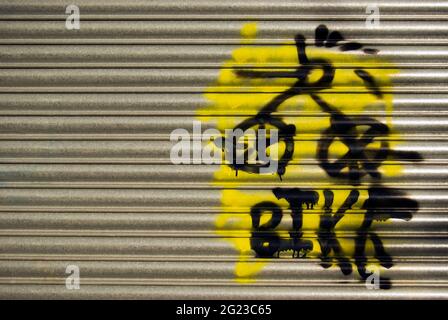 Buntes Fahrrad-Graffiti-Spray auf einen großen Metallladen-Rollo gemalt. Stockfoto