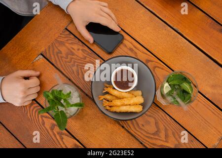 Draufsicht Foto der Hände des Mannes am Couchtisch mit dem Smartphone Stockfoto