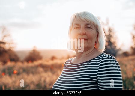 Kaukasische Frau Tourist bei Sonnenuntergang auf dem Feld. Sommerurlaub, die Sonne genießen. Horizontales Banner Stockfoto