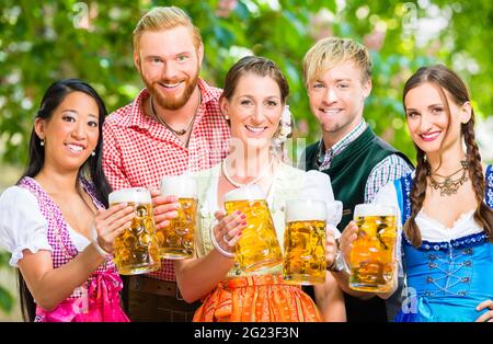 Freunde, zwei Männer, drei Frauen, stehend im Biergarten mit Bier Gläser Stockfoto