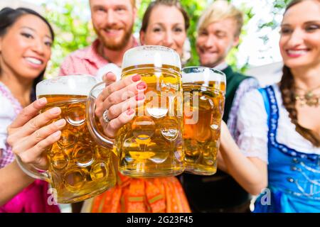 Freunde, zwei Männer, drei Frauen, stehend im Biergarten mit Bier Gläser Stockfoto