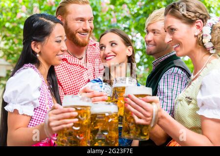 Fünf Freunde, Männer und Frauen, Spaß im Biergarten klirren Gläser mit Bier Stockfoto
