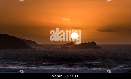 Ein Panoramablick auf einen intensiven spektakulären Sonnenuntergang über der Fistral Bay in Newquay in Cornwall. Stockfoto