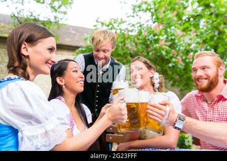 Ive Freunde im Bayerischen Kleidung klirren Biergläser im Biergarten Stockfoto