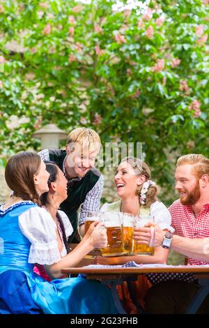 Ive Freunde im Bayerischen Kleidung klirren Biergläser im Biergarten Stockfoto