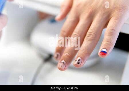 Maniküre in Arbeit - schöne, gepflegte Männernägel mit rotem Nagellack. Die Industrie der Schönheit und Nagelpflege, Schönheitssalons Stockfoto