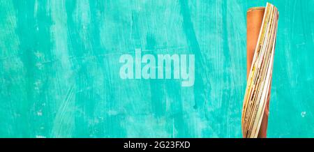 Rollende Zeitung oder Zeitschrift auf grünem Hintergrund, Panoramapresse, Medien, Zeitungsmodell, kostenloser Kopierplatz Stockfoto