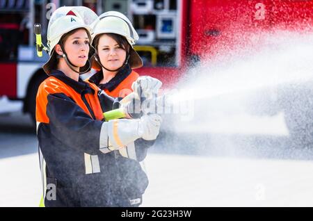 Feuerwehrinnen spucken Wasser, um Feuer zu löschen Stockfoto