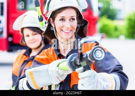 Feuerwehrinnen spucken Wasser, um Feuer zu löschen Stockfoto