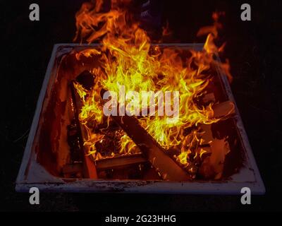 Offenes Feuer brennendes Holz in der Metall-Feuerstelle im Freien bei Nacht, kontrollierte Verbrennung und Flammendetails Stockfoto