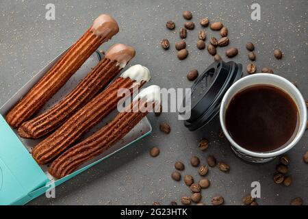 Blick von oben auf Kaffee zum Mitnehmen neben Schokolade gefüllt und einfache Churros. Stockfoto