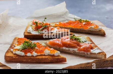 Sandwiches oder Tapas mit Brot, rotem Kaviar und rotem Fisch mit Mikrogemüse, Meeresfrüchten Luxus-Delikatessen Stockfoto