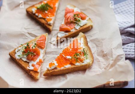 Sandwiches oder Tapas mit Brot, rotem Kaviar und rotem Fisch mit Mikrogemüse, Meeresfrüchten Luxus-Delikatessen Stockfoto