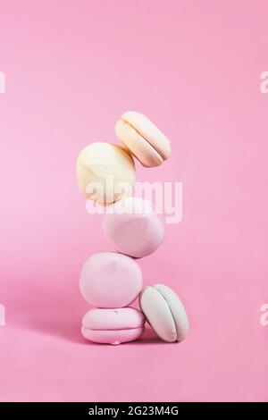 Bunte pastellfarbene Marschmallow Levitation und Balance auf rosa Hintergrund Stockfoto