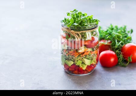 Gemüsesalat im offenen Glas Tomaten, Avocado, Pfeffer, Gurken, Micro Greens gesunde Ernährung, Ernährung, saubere Lebensmittel und vegetarische Konzept Stockfoto