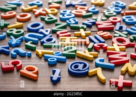 Draufsicht auf bunte Plastikbuchstaben und Zahlen auf Holzhintergrund Stockfoto
