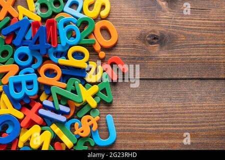 Draufsicht auf bunte Plastikbuchstaben und Zahlen auf Holzhintergrund Stockfoto