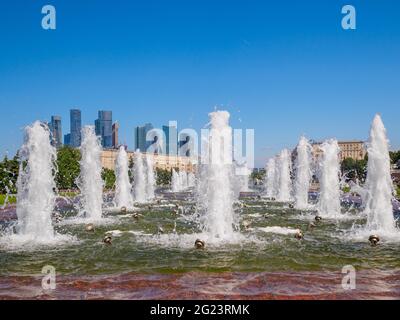 Jets von Springbrunnen an einem sonnigen Tag vor der Kulisse moderner Wolkenkratzer und einem wolkenlosen blauen Himmel. Erholungsgebiet im Victory Park auf Poklonnaya Stockfoto