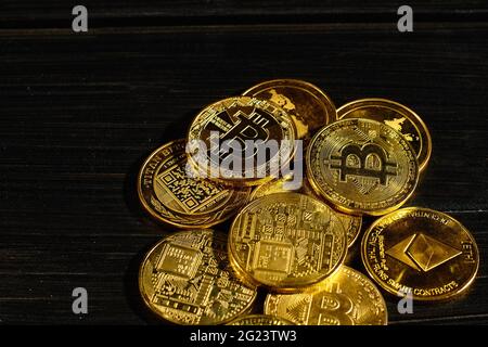Nahaufnahme Goldmünze mit Bitcoin-Logo. Führend in Kryptowährung Bitcoin BTC auf einer Oberseite von Münzen gegen schwarze Holzoberfläche. Haufen dezentraler Stockfoto