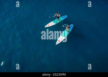 28.Mai 2021. Anapa, Russland. Paar auf Stand Up Paddle Board am blauen Meer. Menschen, die auf Red Paddle gehen, supboard im Ozean. Luftaufnahme Stockfoto