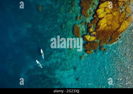 28.Mai 2021. Anapa, Russland. Paar auf Stand Up Paddle Board am blauen Meer. Menschen, die auf Red Paddle gehen, supboard in transparentem Meer. Luftaufnahme Stockfoto